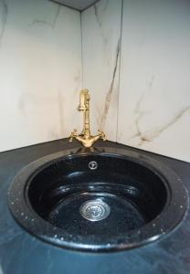a black bathroom sink with a gold faucet at Small paradise by the old bridge in Chalkida