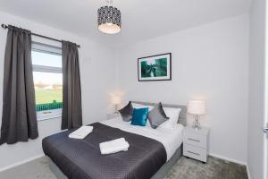 sypialnia z łóżkiem z niebieskimi poduszkami i oknem w obiekcie Damwood House w Liverpoolu