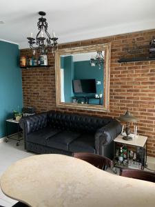 a living room with a black leather couch and a mirror at Hermoso departamento un dormitorio in Santa Fe