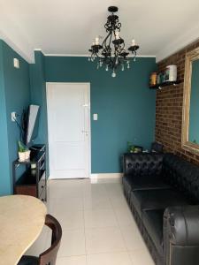 uma sala de estar com um sofá preto e uma parede azul em Hermoso departamento un dormitorio em Santa Fé