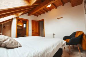 a bedroom with a white bed and a chair at Le Héron 28pers, Malmedy- Home cinéma, balnéo, sauna, jardin in Malmedy +35 photos