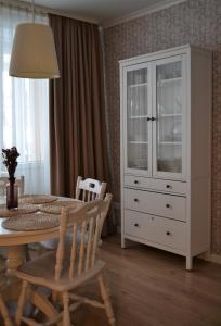 a dining room with a table and a white cabinet at Šaulys in Druskininkai