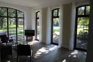 a living room with large windows and a flat screen tv at Ferienhaus auf Gut Sautmannshausen in Haselünne
