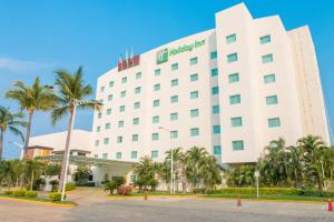 a large white hotel with palm trees in front of it at Holiday Inn Acapulco La Isla, an IHG Hotel in Acapulco
