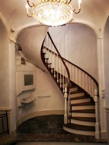 ein Kronleuchter hängt über einer Wendeltreppe in einem Gebäude in der Unterkunft JARDIN D'HIVER CASSEL in Cassel