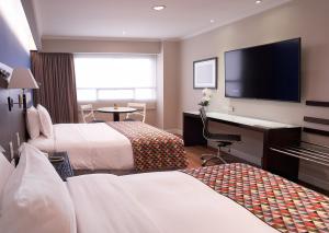 a hotel room with two beds and a desk and a television at Oro Verde Guayaquil in Guayaquil