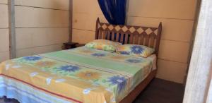 a bedroom with a bed with a flower blanket and pillows at Centro Ecoturistico Ya´ajche in Lacanjá