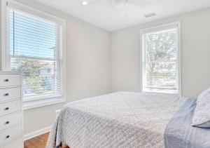 a white bedroom with a bed and two windows at Stylish house one block to beach with linens and parking in Point Pleasant Beach