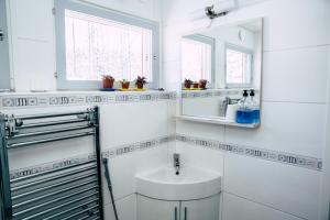 a white bathroom with a sink and a mirror at Poppelstrand Nuuksio, Pet friendly guest apartment in Nuuksio