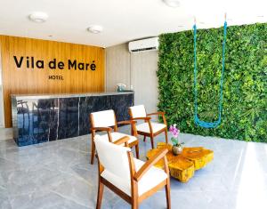 Cette chambre comprend une table, des chaises et un mur vert. dans l'établissement Vila de Maré Hotel, à Porto de Galinhas