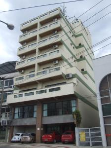 a tall building with cars parked in front of it at Stratus Centro Hotel in Volta Redonda