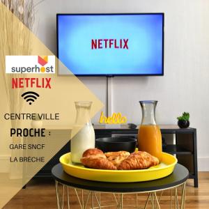a table with a plate of food and a tv at Luxury-Centre-Ville -Gare-netflix Wifi in Niort