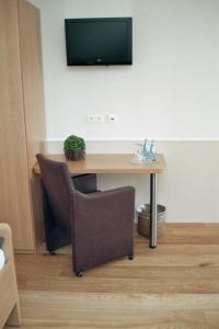 a desk with a chair and a television on a wall at Hotel Franke in Alstätte