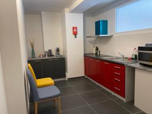 una cocina con armarios rojos y una silla amarilla en Gîtes Sax 3 en Dinant