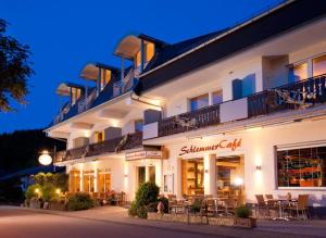 a large white building with tables and chairs in front of it at NaturPurHotel Maarblick in Meerfeld
