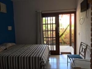 a bedroom with a bed and a sliding glass door at Pousada Cravo e Canela in Itaúnas