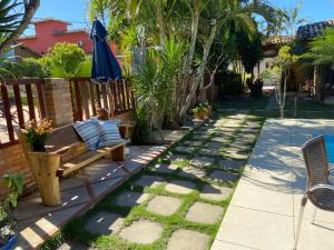 a garden with a bench and an umbrella at Pousada Cravo e Canela in Itaúnas