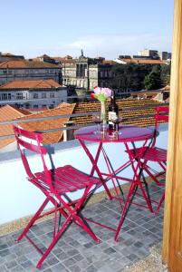Apartments Porto Historico في بورتو: طاولة حمراء وكرسيين على شرفة