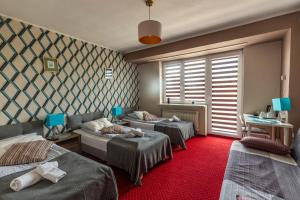 Pokój z 3 łóżkami i czerwonym dywanem w obiekcie Villa Kava w Warszawie