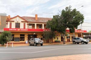 a building with two trucks parked in front of a street at New Crown Hotel Motel in Hay