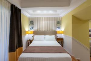 Bett in einem Zimmer mit gelben Wänden und 2 Lampen in der Unterkunft Palazzo Turchini in Neapel