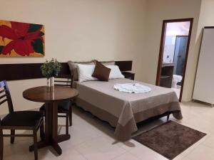 um quarto com uma cama, uma mesa e uma cadeira em Hotel Martins em Pouso Alegre