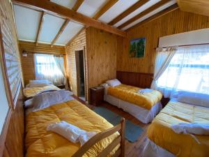 Cabañas y Hostel Isla Magica في أنكود: غرفة نوم بثلاث اسرة في غرفة
