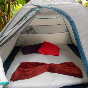 a bed in a tent with a red blanket at Camping Trópico de Capricórnio - Ilhabela in Ilhabela