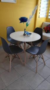 einen Tisch mit vier Stühlen und eine Vase mit einer Blume darauf in der Unterkunft departamento paraiso estrella Raquet Club in San Juan Cosalá