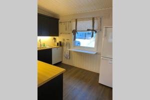 a kitchen with a white refrigerator and a window at Koselig hus til leie på Stokmarknes i Vesterålen in Stokmarknes