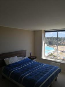 1 dormitorio con cama azul y ventana grande en DEPTO LAGUNA BAHIA MARINA, en Algarrobo