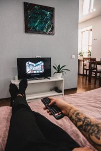 une personne posant sur un lit tenant une télécommande dans l'établissement ART apartment, à Jytomyr