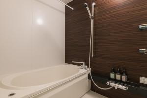 a bathroom with a white tub and a wooden wall at GRAND BASE Kagoshima Tenmonkan in Kagoshima +34 photos