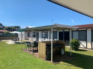 eine überdachte Terrasse mit einem Tisch und einem Grill in der Unterkunft Robe Nampara Cottages in Robe