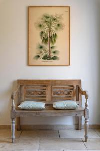 a wooden bench with two pillows sitting under a picture at Boulevard du Soleil in Bormes-les-Mimosas