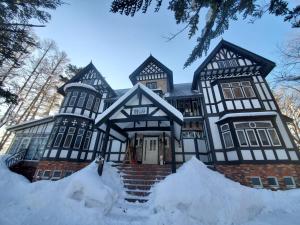a large black and white house covered in snow at プチホテル葡萄屋 in Hakuba