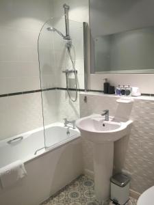 W łazience znajduje się umywalka, wanna i prysznic. w obiekcie Liberty Suite Apartment w mieście Portishead