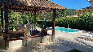 a backyard with a swimming pool and a wooden pavilion at Casa de 5 suítes e piscina em Geribá in Búzios