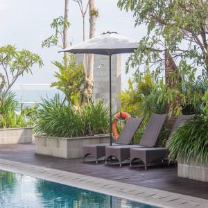 Una sombrilla y sillas junto a una piscina. en The Cabin Apartment Uttara, en Yogyakarta 23 fotos más