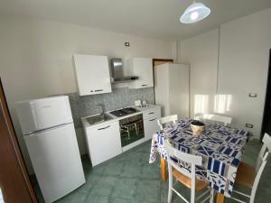una cucina con tavolo, sedie e frigorifero di Petra Marina Maris a Pisciotta