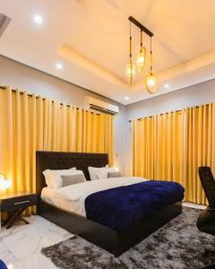 a bedroom with a large bed with yellow curtains at The Avery Suites, East Legon in Accra