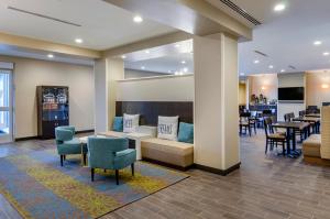 uma sala de espera com cadeiras e mesas e um bar em MainStay Suites Great Falls Airport em Great Falls