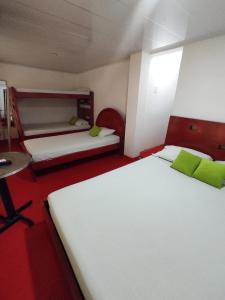a bedroom with two beds and a desk and a table at Hotel Casablanca Cañaveral in Floridablanca