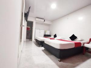 Zimmer mit 3 Betten und einem Spiegel in der Unterkunft Hotel Casablanca Cañaveral in Floridablanca