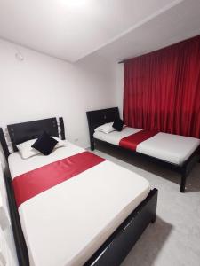 two beds in a room with red curtains at Hotel Casablanca Cañaveral in Floridablanca