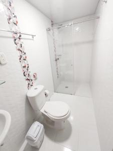a white bathroom with a toilet and a shower at Hotel Casablanca Cañaveral in Floridablanca