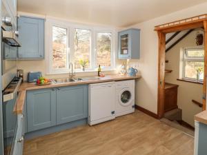 een keuken met een wastafel en een wasmachine bij Min Y Traeth in Amlwch