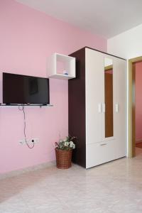 a room with a tv on a pink wall at Apartments Ivo - family friendly in Zaton