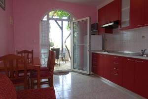 a kitchen with red cabinets and a table and a dining room at Apartments Ivo - family friendly in Zaton