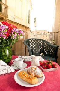 una mesa con pan y fresas sobre un mantel rojo en Leccesalento Bed And Breakfast, en Lecce